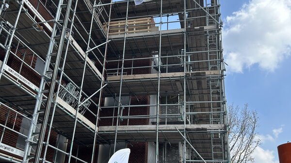 Feestelijk moment op Bakelgeertterrein: vlag wappert op hoogste punt  nieuwbouw 